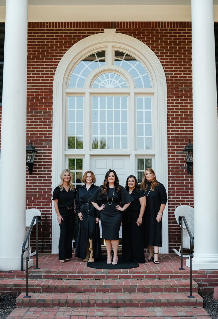 The Kemp and Associates Team Posing Together on elegant staircase