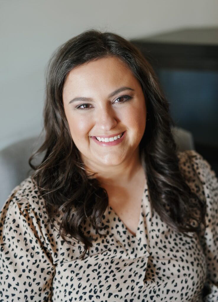 Headshot of team member, Rachel in beige and black shirt smiling